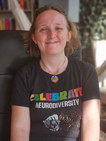 Rosemary Richings smiling and proudly wearing a celebrate neurodiversity t-shirt. The shirt itself is a proud statement of her pride in her neurodivergence.